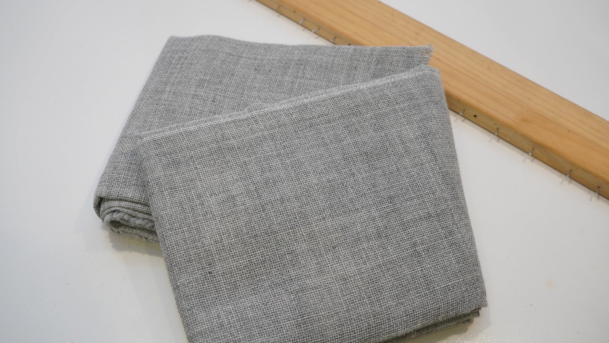 Close view of grey primary tufting cloth weave and folded edge