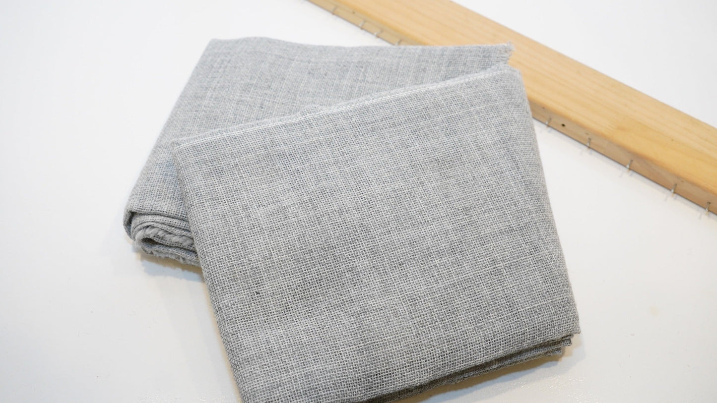 Grey premium primary tufting cloth folded beside a wooden tufting frame