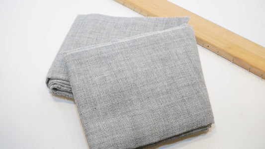 Grey premium primary tufting cloth folded beside a wooden tufting frame