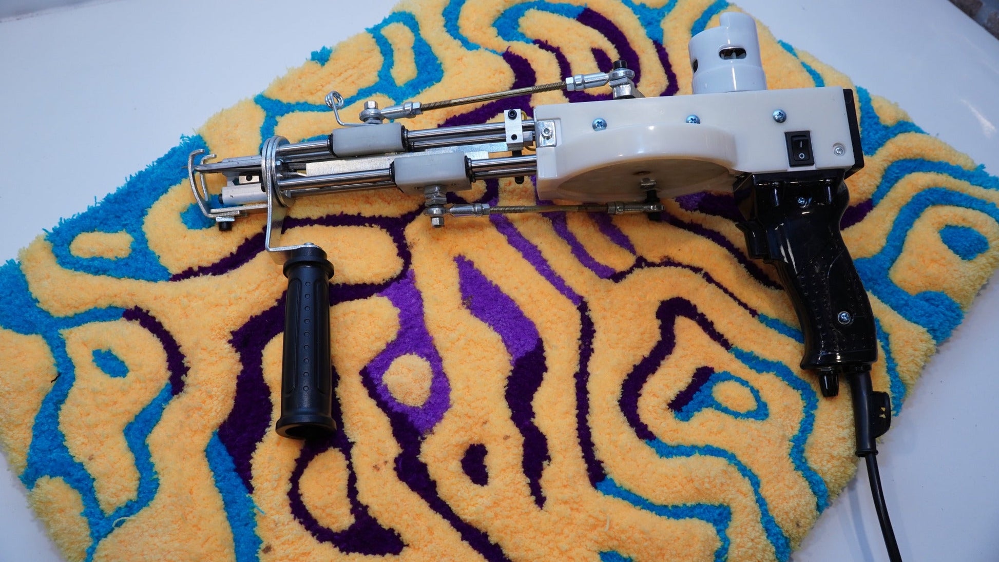 Long AK-V Pro tufting gun displayed on a finished handmade rug