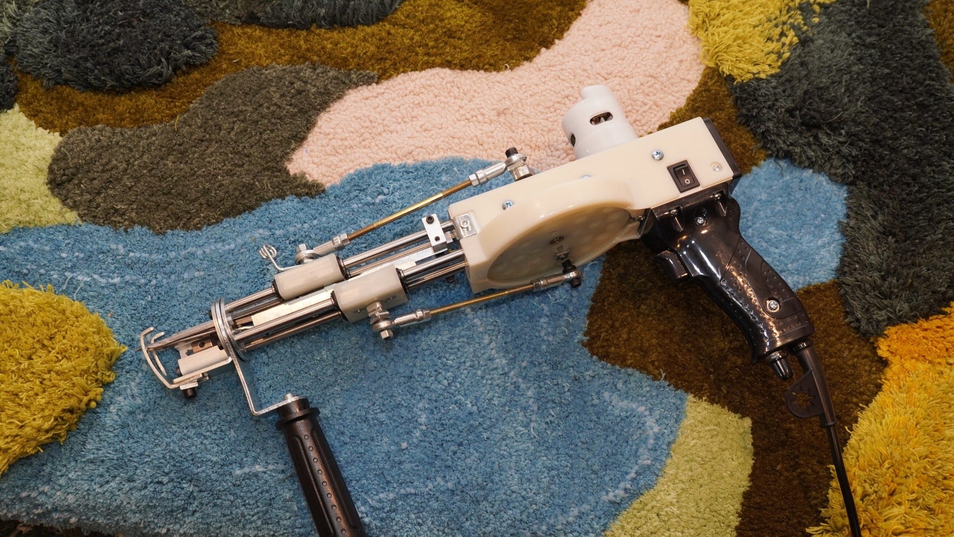 Long AK-V Pro tufting gun positioned on a finished studio rug